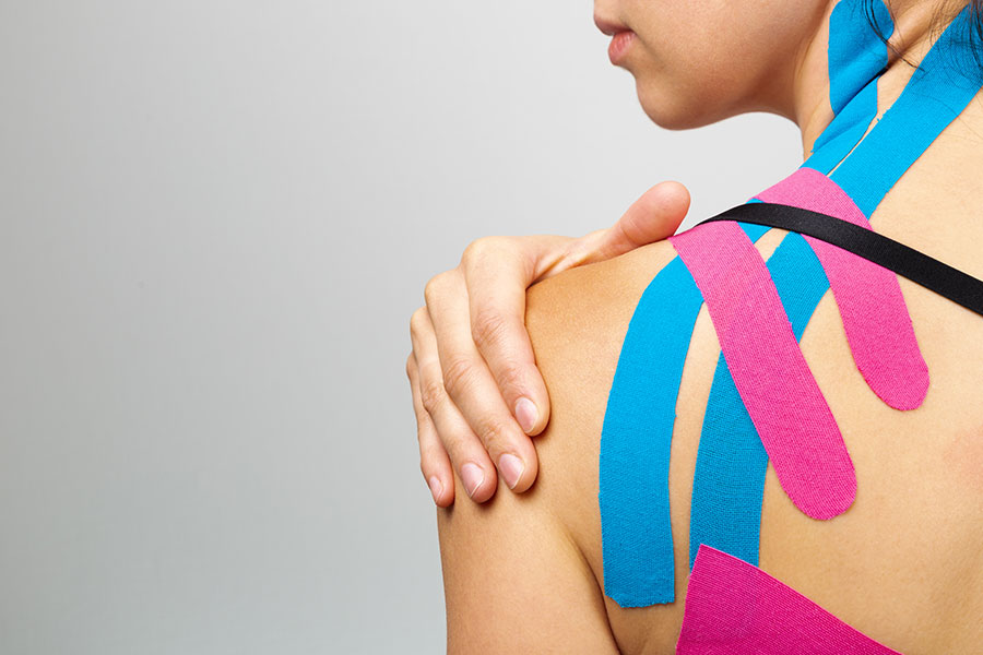 Žena s páskou kinesiotape na rameni.