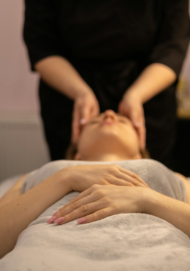Relaxační masáž zad – masérka jemně masíruje záda ženy ležící na lehátku.